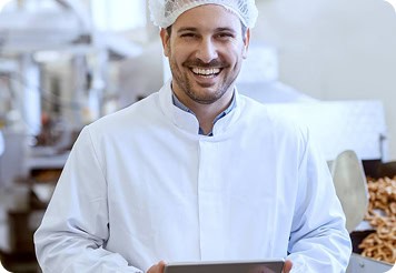 Professional chef in white uniform smiling in kitchen setting.
