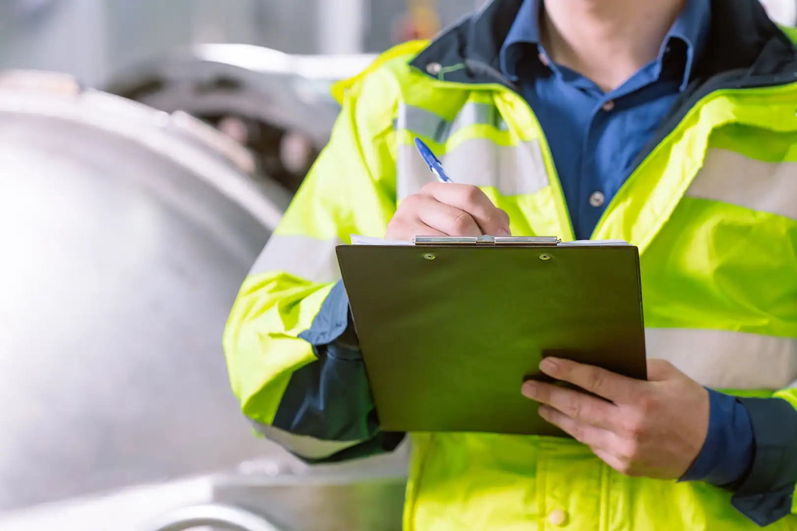 Waste management professional inspecting waste processes with clipboard in industrial setting.
