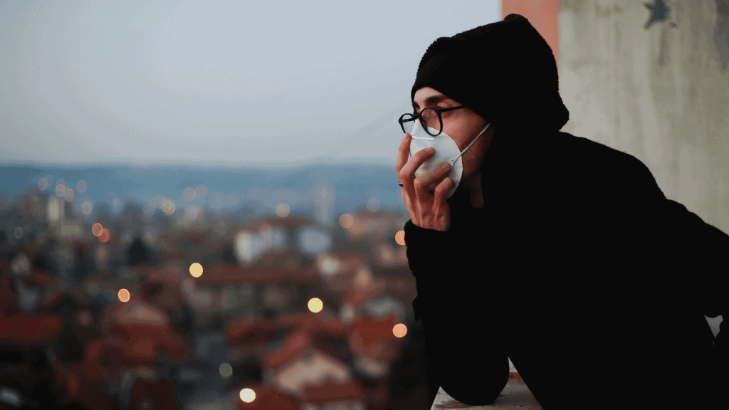 Woman wearing mask contemplating waste impact on health in urban area.