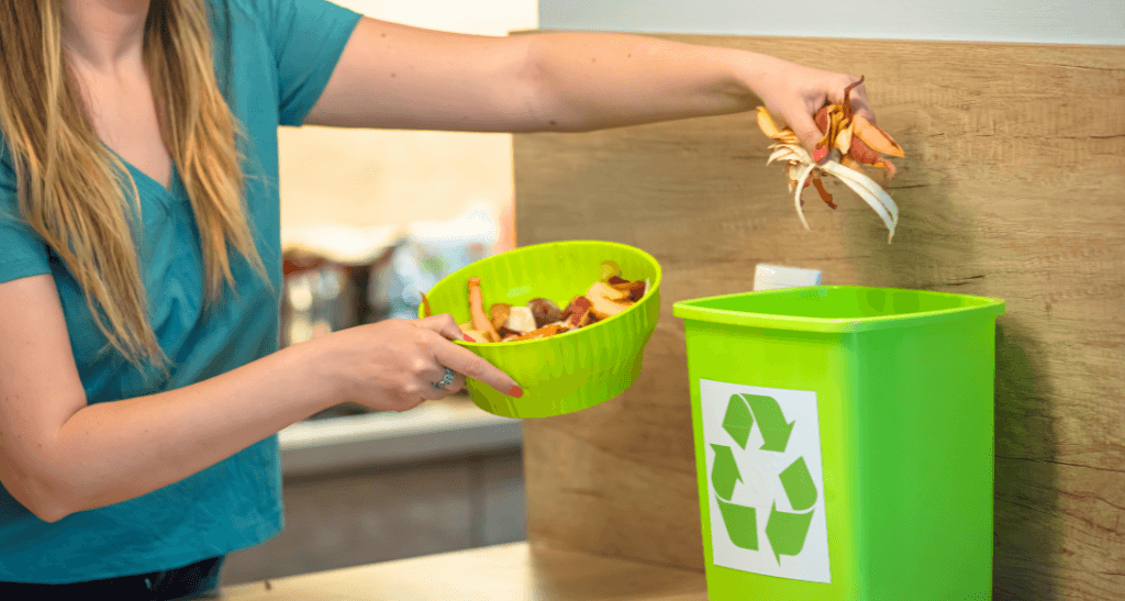 Person disposing food waste into a recycling bin for composting at Eco-Friendly event.
