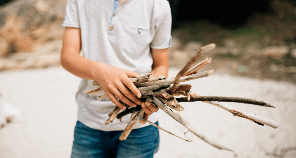 Child holding eco-friendly wood sticks for sustainable waste solutions.