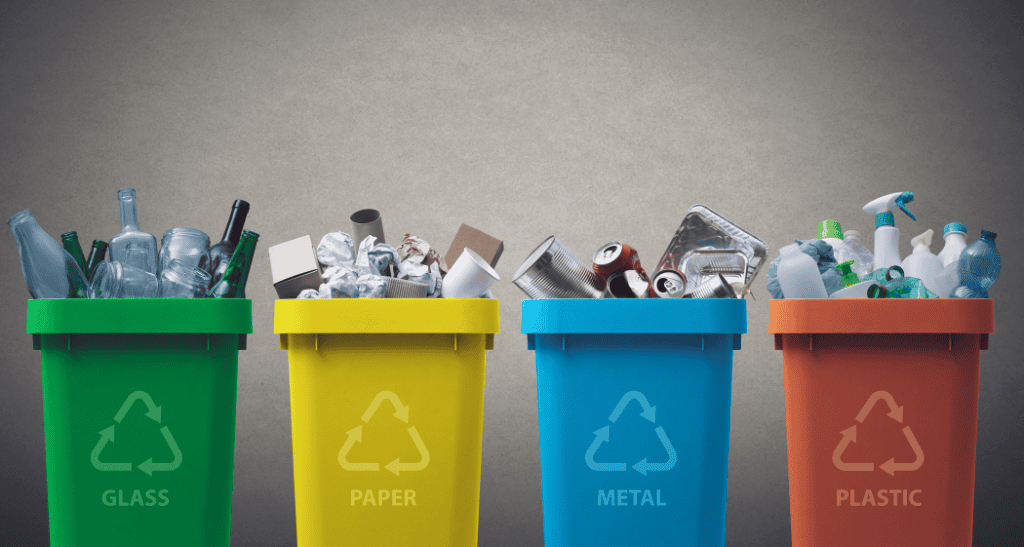 Color-coded recycling bins for glass, paper, metal, and plastic waste sorting.