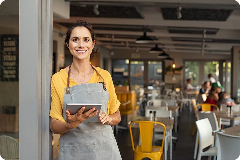 Restaurant staff member holding a tablet in a modern dining area.