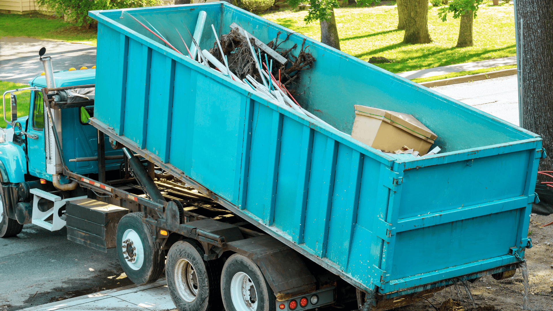 Blue waste disposal truck collecting construction debris and waste materials.