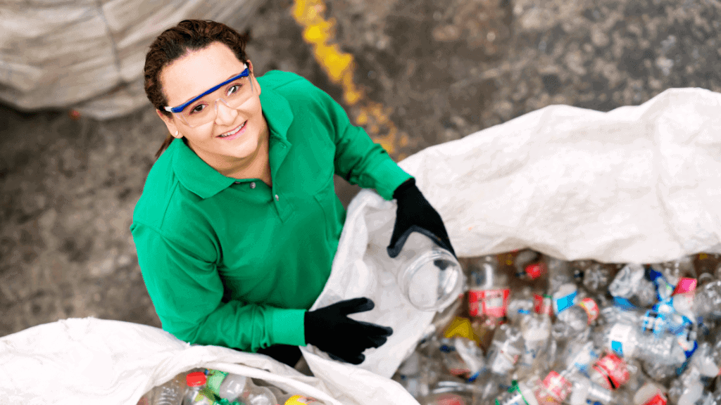 Woman recycling plastic bottles at waste disposal site.