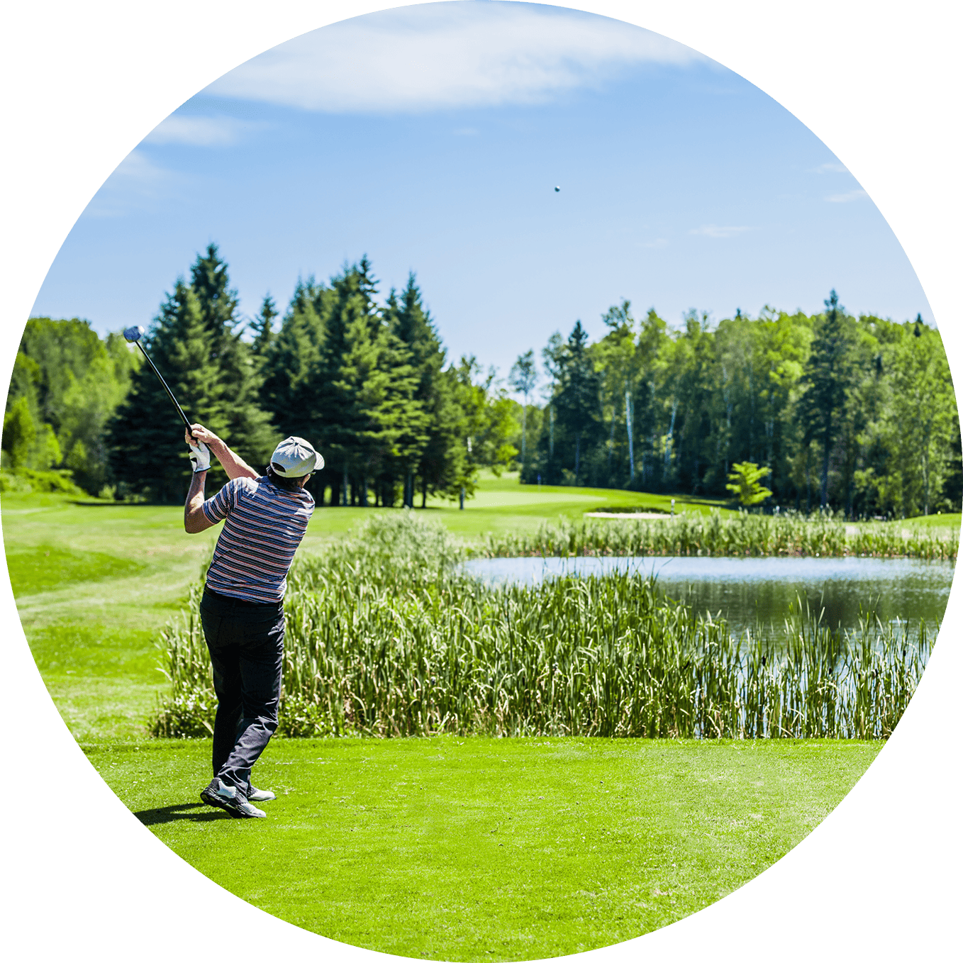 Golf course with lush greenery and water features under a clear blue sky.