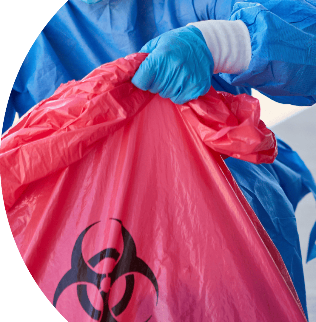 Worker handling hazardous waste bag with biohazard symbol.